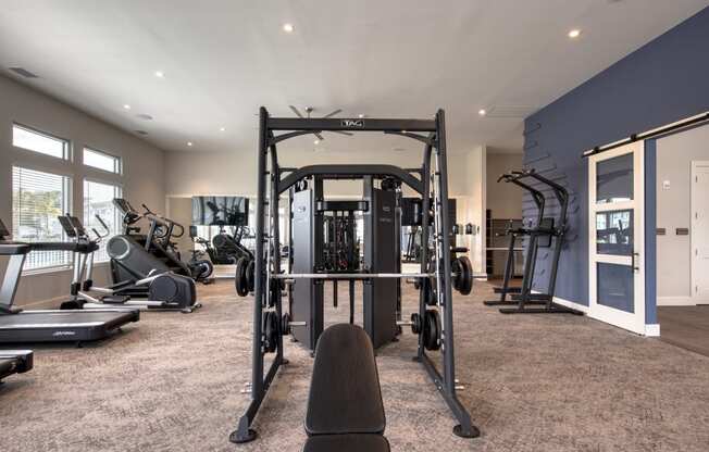 a gym with weights and cardio equipment on the floor and a window