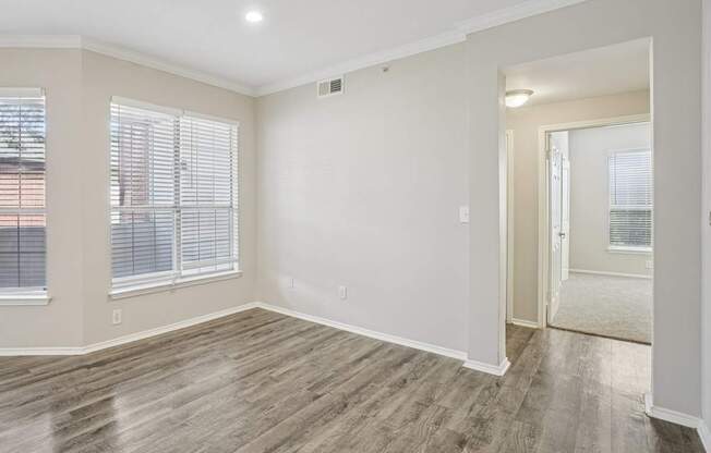 A room with wooden flooring and a window with blinds.
