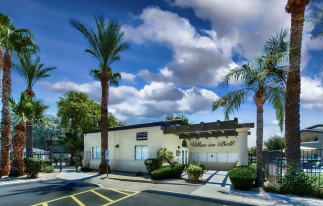 a building with palm trees in front of it at Villas on Bell, Phoenix, AZ 85053