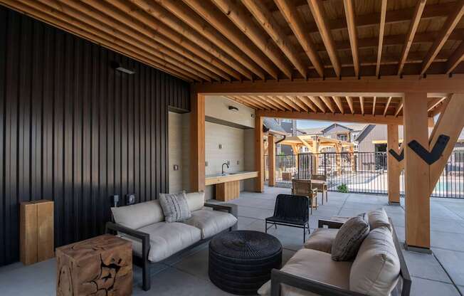 A modern outdoor living space with a wooden ceiling and black wall.