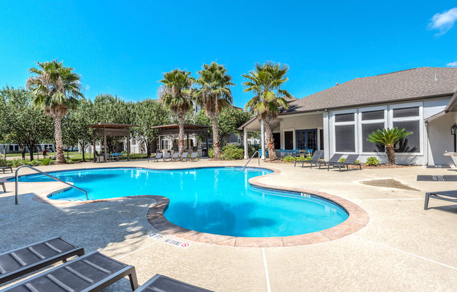 A swimming pool surrounded by palm trees and lounge chairs.