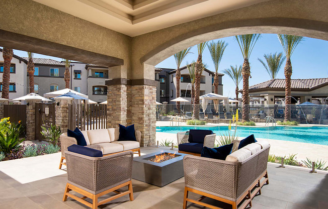 a covered patio with wicker furniture and a fire pit