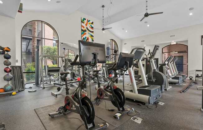 A gym with a variety of exercise equipment including treadmills, stationary bikes, and weight machines.
