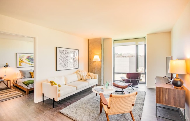 A well-lit, modern living room with a white sofa and a wooden chair.