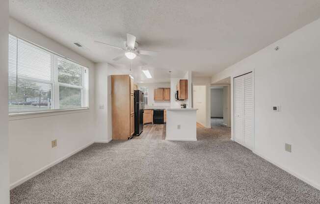 A spacious kitchen with a refrigerator, cabinets, and a ceiling fan.