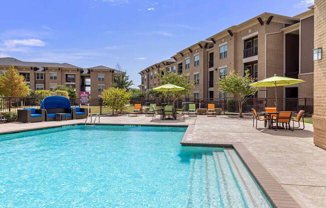 a swimming pool with chairs and umbrellas in front of a building