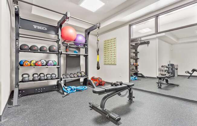 A gym with a variety of equipment including weights and a bench.