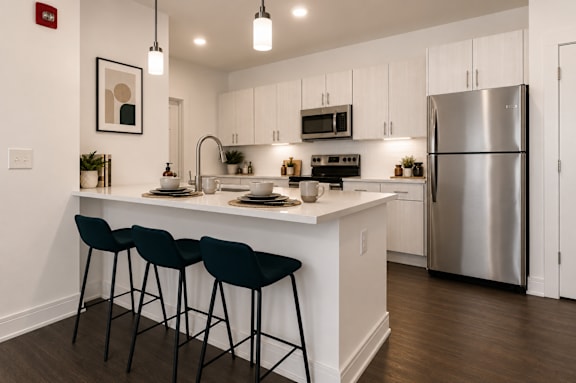 A modern kitchen with a white countertop and black barstools.