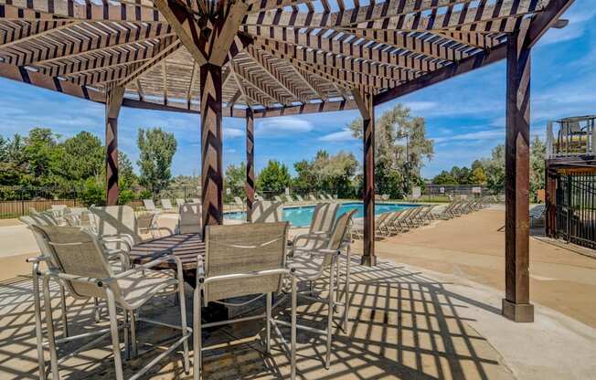A patio with a table and chairs under a wooden pergola.