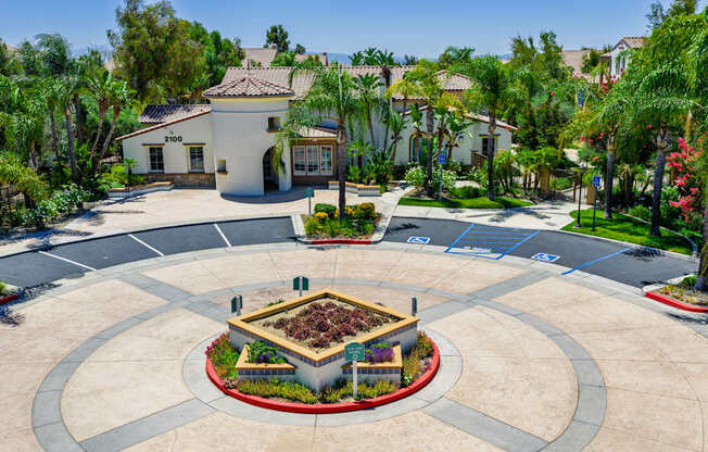 A roundabout with a garden in the middle is surrounded by houses and trees.