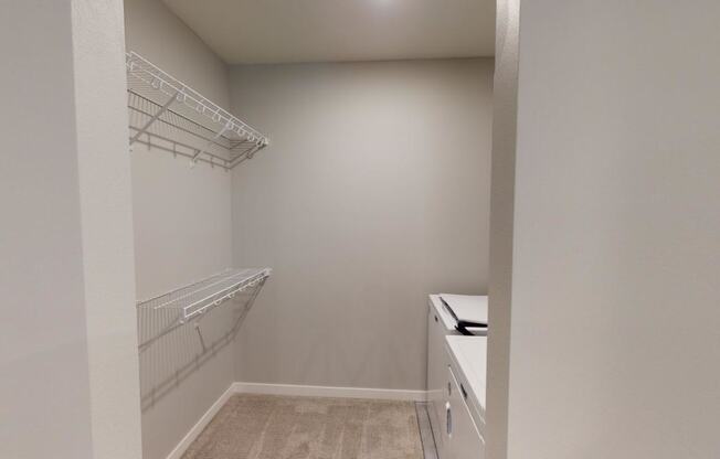 a walk in closet in a home with white walls and shelves