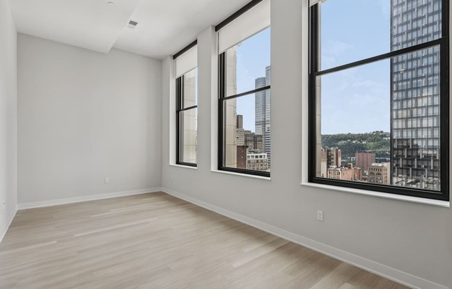 A large empty room with a view of the city through the windows.
