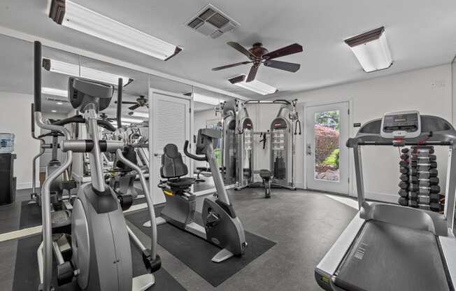 a gym with cardio equipment and a ceiling fan