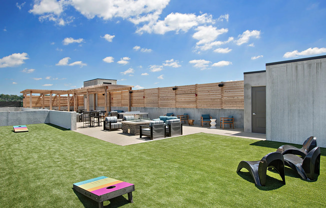 Outdoor entertainment area at our apartments in Atlanta, featuring cornhole, astroturf, and outdoor seating.