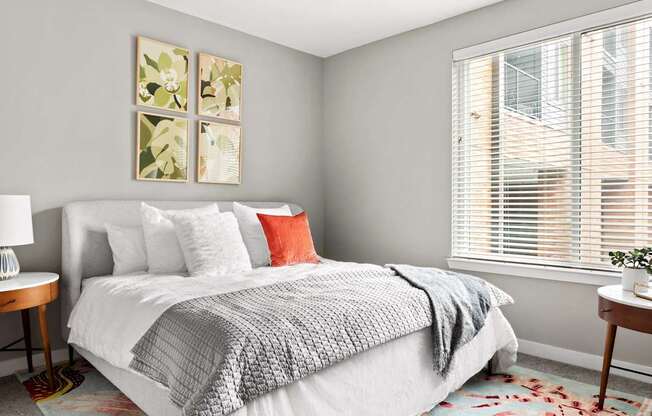 A bedroom with a large bed and a window with blinds.