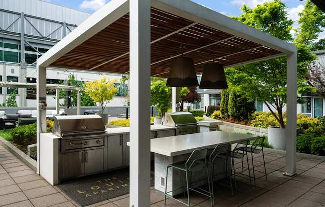 A white outdoor kitchen with a grill and table.