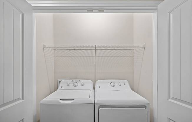 a white laundry room with two washes and a dryer