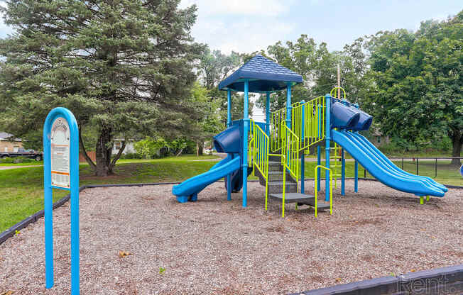 A playground with a blue slide and yellow railing.
