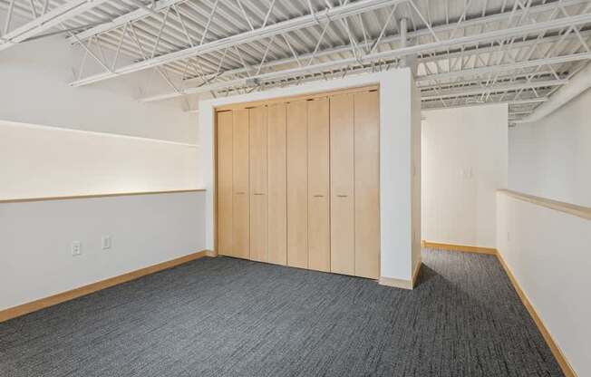 A room with a grey carpet and a wooden door.