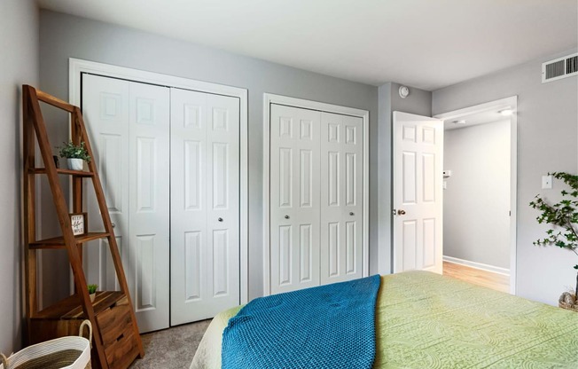 a bedroom with two closets and a bed with a blue blanket