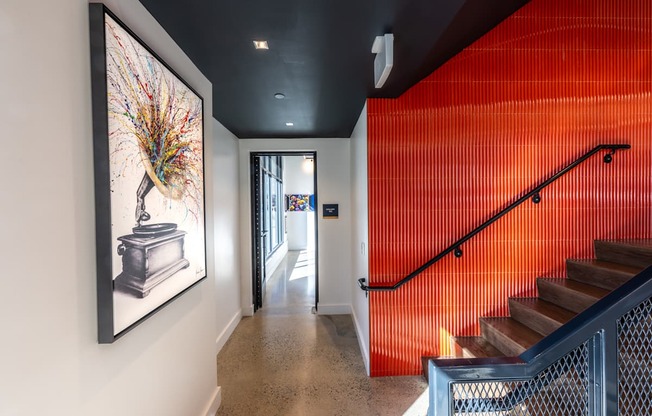 A hallway with a staircase and a painting of a peacock on the wall.
