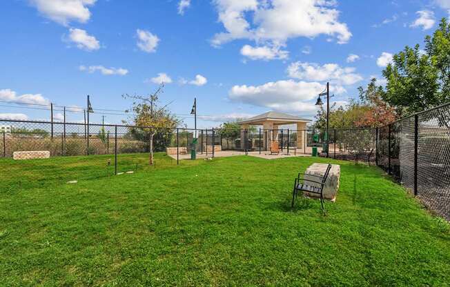 A grassy field with a fence and a gazebo in the distance.