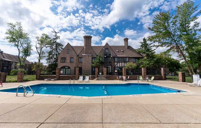 a swimming pool in front of a large brick house with a pool