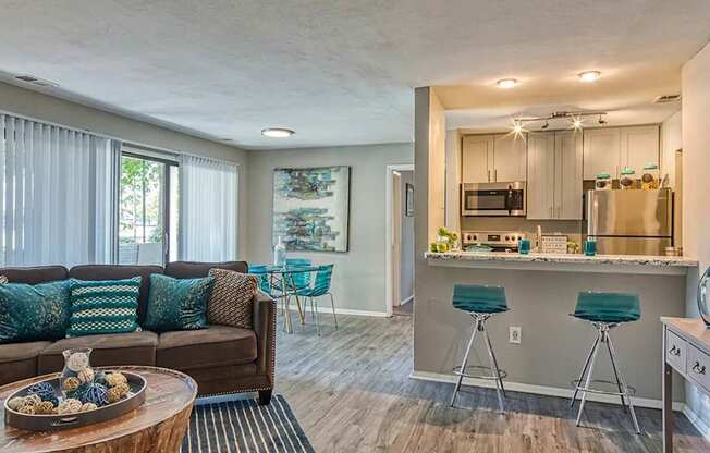 A modern living room with a wooden coffee table and a kitchen area in the background.
