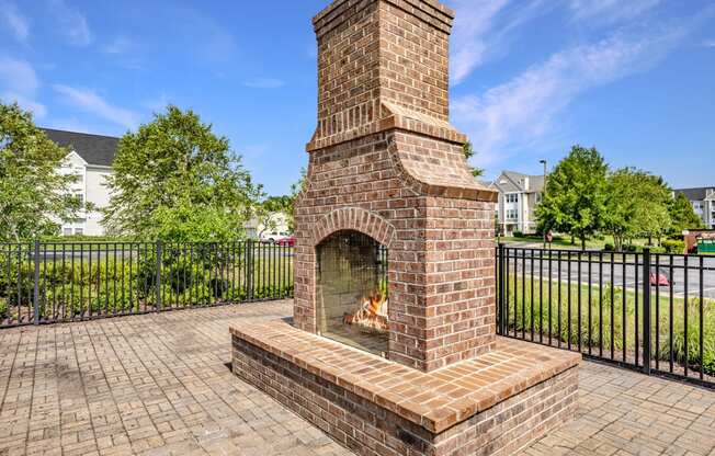 an outdoor brick fireplace with a stone mantel sits on a brick patio in front of a