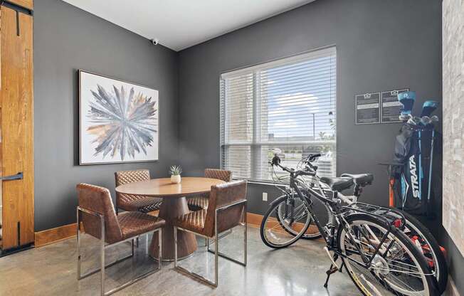A room with a dining table and chairs and a bicycle.