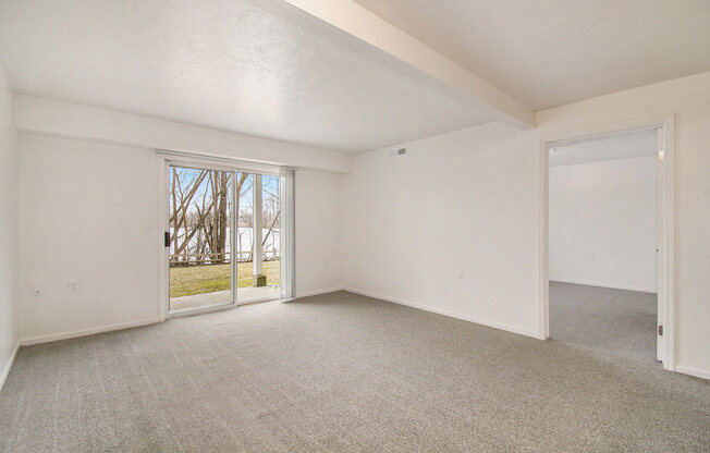 living room with a slider to a patio overlooking the landscaped grounds at Canal 2 Apartments in Lansing, MI