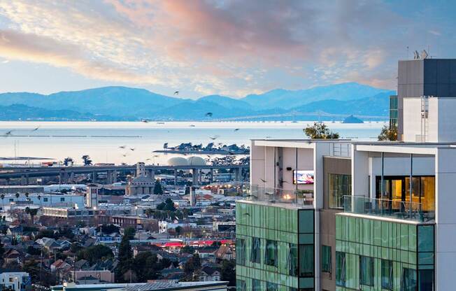 A cityscape with a large body of water and mountains in the background.