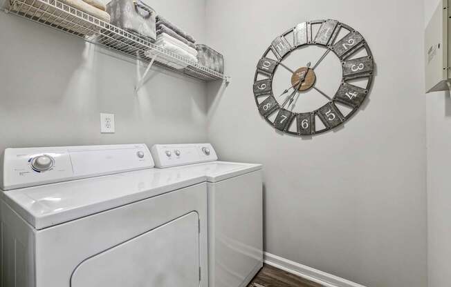 A laundry room with a washer and dryer and a clock on the wall.