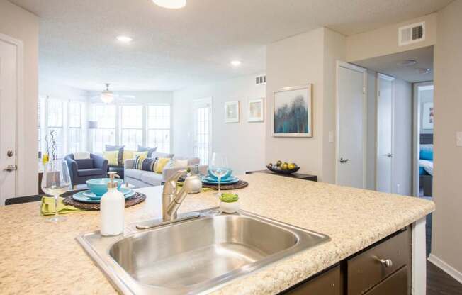 a kitchen counter top with a sink and a living room