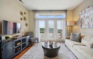 a living room with a couch and a tv and a balcony at Link Apartments® Brookstown, Winston Salem