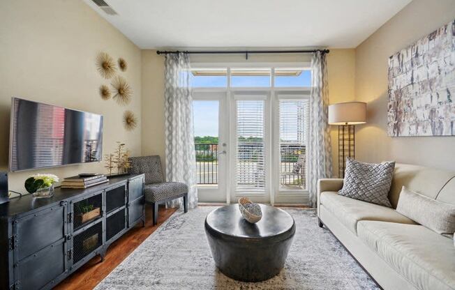 a living room with a couch and a tv and a balcony at Link Apartments® Brookstown, Winston Salem