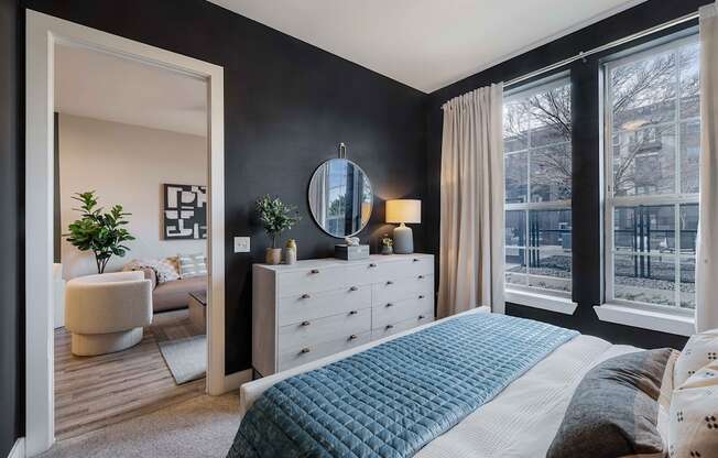 a bedroom with a bed and a dresser    and a large window