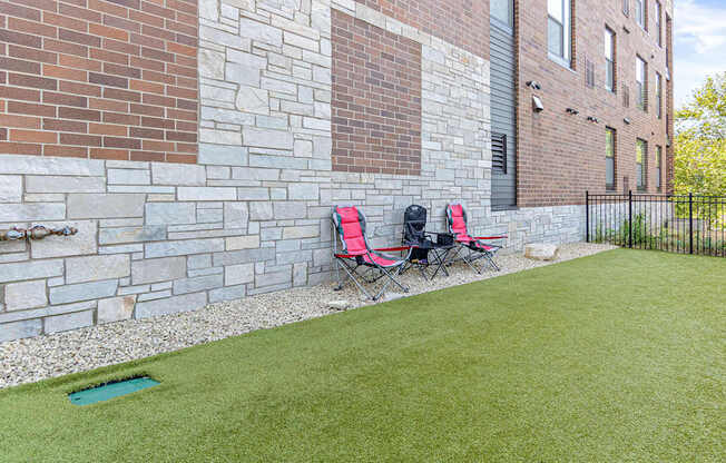 Two red chairs are placed on a green lawn.