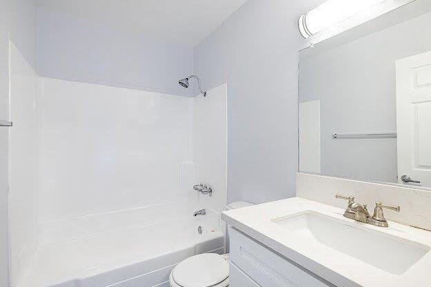 A white bathroom with a toilet, sink, and shower.