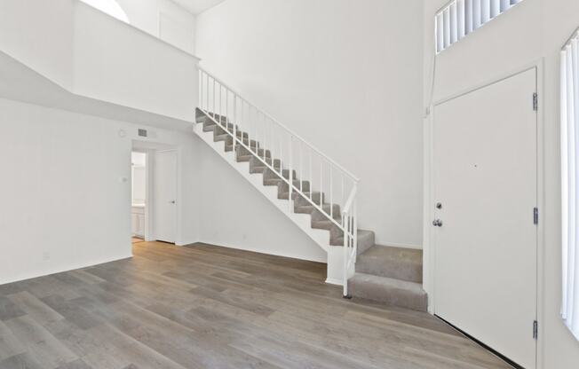 a white room with a staircase and a door to a hallway and a white door