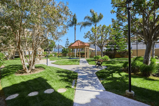 a pathway through a park with a gazebo and trees at Huntington Terrace North Senior, California