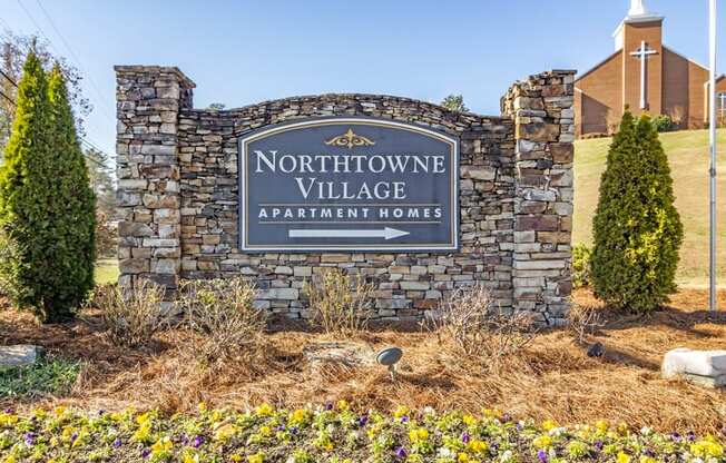 a sign for northshore village apartments with a church in the background
