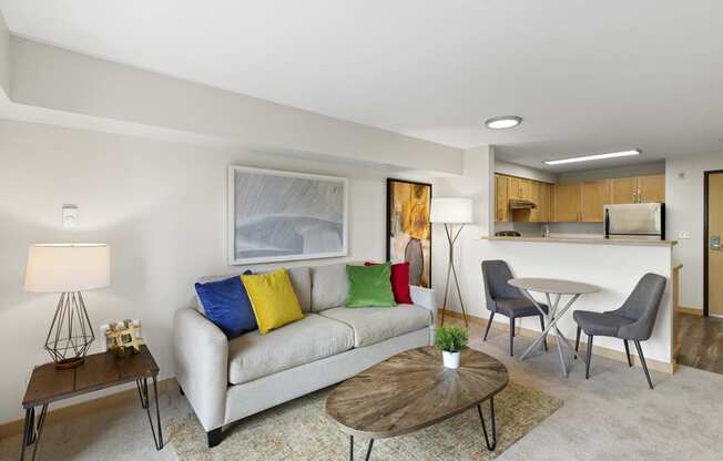 a living room with a couch, table, and a bistro set and a kitchen in the background at Villaggio Apartment Homes, Tacoma, WA