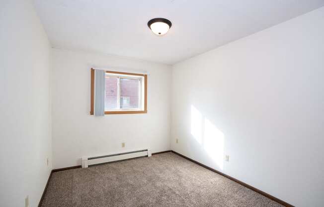 an empty room with carpet and a window. Fargo, ND Country Club Apartments