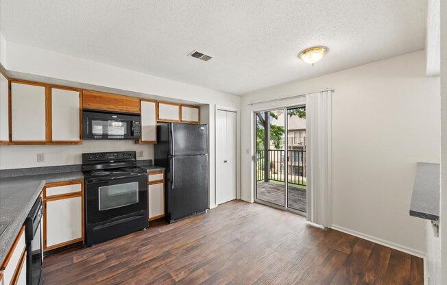 an empty kitchen with black appliances and a sliding glass door