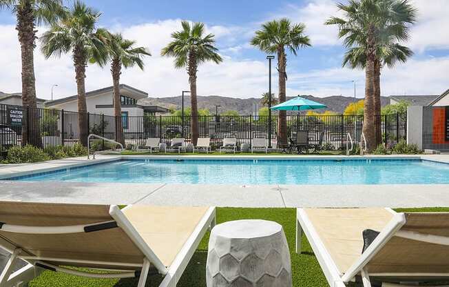 a swimming pool with palm trees and houses in the background