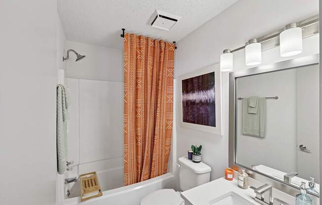 A bathroom with orange curtains and a white toilet.