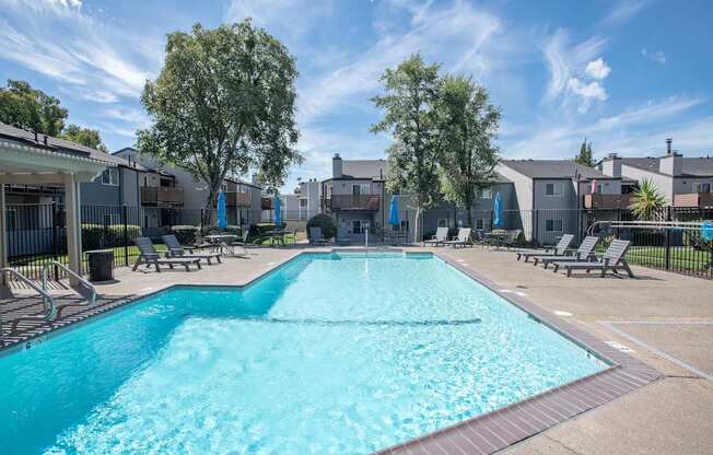 A large swimming pool surrounded by lounge chairs and trees at Sierra Glen Apartments, California, 95621