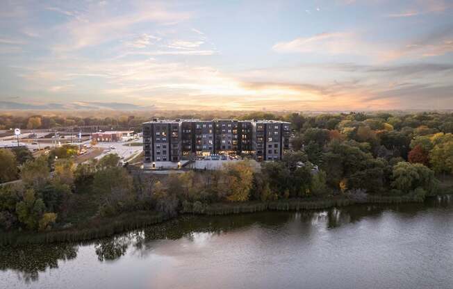 A modern building is situated by a body of water with trees in the background.