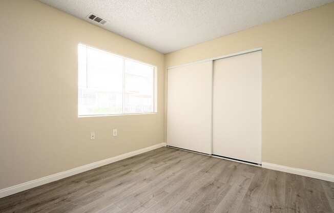a bedroom with two closets and a window at Sagewood Gardens Senior Apartments, California